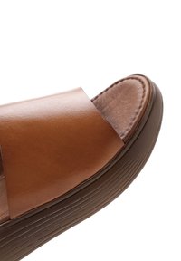 Sandalo scivolante in pelle marrone con ampia fascia, soletta imbottita e suola flessibile testurizzata con striature orizzontali.