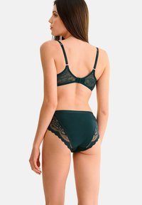 Ensemble de soutien-gorge en dentelle vert foncé et de culotte taille haute présentant des bords festonnés, des bretelles ajustables et un motif floral en dentelle sur les côtés.