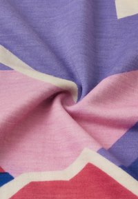 Dzianina w odcieniach fioletu i różu, z geometrycznymi wzorami. Miękka tekstura z lekkim połyskiem i kontrastującymi białymi akcentami.