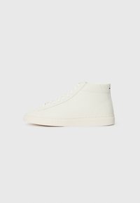 Zapatillas altas en material texturizado blanco con punta redondeada suave y suela de goma plana. Presentan un diseño de cordones y una marca mínima.