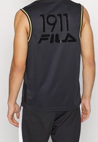 Schwarzes ärmelloses Sporttrikot mit Netzstruktur, das glänzende Logos "1911" und "FILA" in kontrastierenden Farben zeigt. Goldene Akzente an den Schulternähten.