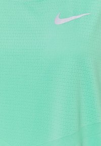 Tissu sportif léger vert clair et respirant avec de petits trous de ventilation et un logo Nike Swoosh argenté près du haut.
