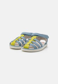 Blaue und gelbe Leder-Sandalen mit offener Zehe, Riemendesign und strukturiertem weißen Gummisohle. Merkmale sind Kreuzriemen und ein Klettverschluss.