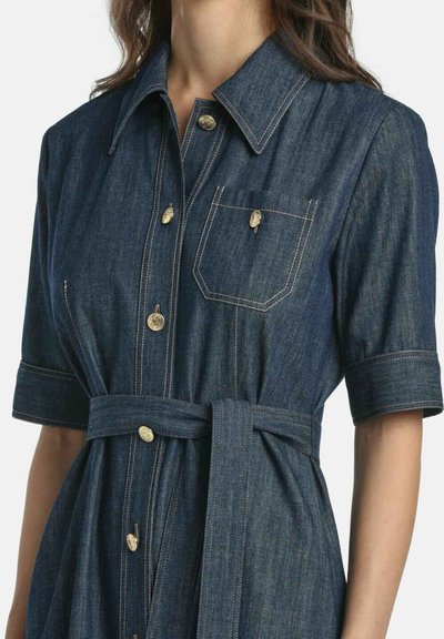 Sötétkék farmering ruha rövid ujjakkal, arany gombokkal, mellzsebbel és hozzáillő övvel a deréknál. Kiemelt varrásokkal.