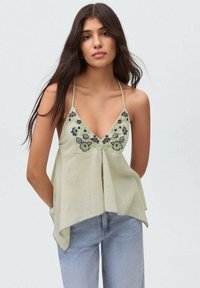 Light green halter top with floral embroidery and a V-neckline, featuring a flared design that tapers at the hem and decorative stitching.