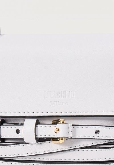 Λευκή δερμάτινη τσάντα Moschino Milano με ραμμένο ρυθμιζόμενο λουρί και λεπτομέρεια αγκράφας σε χρυσαφί τόνο.