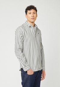 Camicia a maniche lunghe grigia e bianca a righe con colletto button-down, realizzata in tessuto morbido. Presenta un piccolo logo ricamato sul petto.