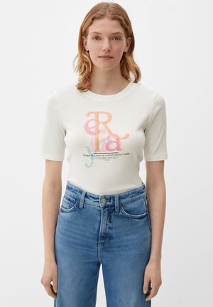 T-shirt blanc à manches courtes en coton doux, présentant un design de texte superposé coloré et une citation imprimée. Associé à un jean taille haute bleu clair.