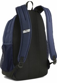 Mochila azul marino con correas de hombro acolchadas, panel trasero de malla negra, bolsillo lateral de malla y un logo plateado de Puma sobre una franja.