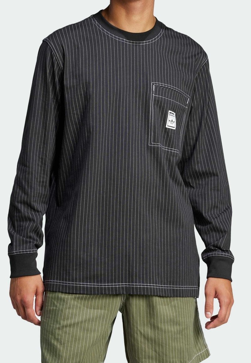 Svart långärmad skjorta med vita smala ränder, som har en framficka med etikett, rund halsringning och kontrasterande manschetter.