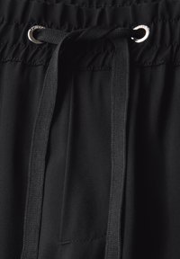 Černé sportovní šortky s elastickým pasem, které mají stahovací šňůrku s kovovými očky a hladkou, lehkou látku.