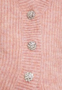 Cardigan a coste rosa con tre bottoni decorativi in tono argento che presentano dei cluster di gemme circolari al centro.