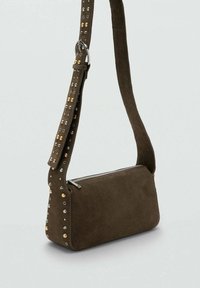 Bolso de hombro de ante marrón con forma rectangular, cierre de cremallera y correa con tachuelas que presenta detalles en dorado y plateado.