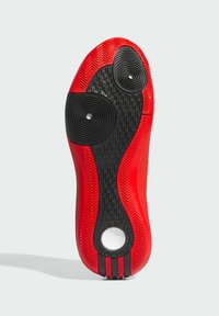Suela de zapato atlético con goma roja y un diseño de tracción negra texturizada, acentos circulares y un corte circular blanco. Dos rayas negras en el talón.