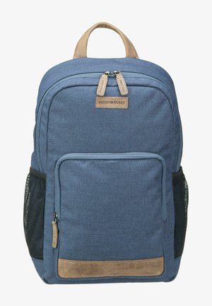 Sac à dos en tissu bleu avec une base en cuir tan, comportant deux compartiments zippés et des poches latérales en mesh pour les bouteilles d'eau.