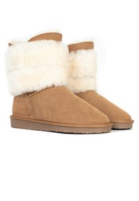 Tan mockaskinnankelstövlar med en mjuk, vit faux fur-krage, rund tå och en texturerad, platt gummisula.