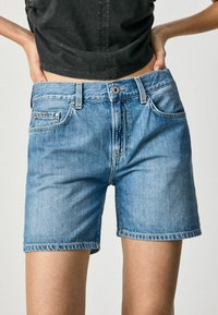 Ljusblå jeansshorts med avspänt snitt. Har fem fickor, knappstängning och en liten varumärkeslapp på framsidan av fickan.