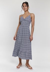 Marinblå blommönstrad midiklänning med tunna axelband, figurnära bodice och utsvängd kjol. Lättviktig tyg, mjuk textur och subtila vita accenter.