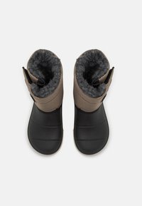 Brown fabric boots with a black rubber sole, soft gray lining, and an adjustable strap at the top for a secure fit.