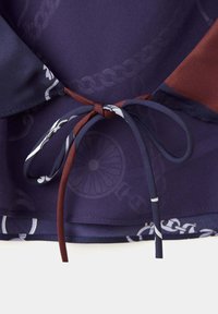 Tissu bleu marine et marron noué en nœud avec un motif imprimé de chaîne et de roue sur un matériau texturé.