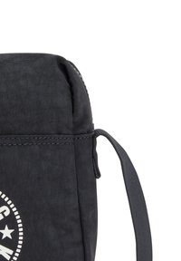 Borsa di stoffa nera con una texture liscia, parte superiore arrotondata, tracolla e una grafica rotonda bianca con stelle e testo.