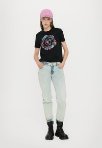 Svart bomull T-skjorte med blomstergrafikk, lyseblå høyt liv jeans, og svarte militærstøvler. En rosa caps fullfører antrekket.