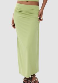 Lange, groene, rekbare rok met een zacht geraffineerde tailleband. Gladde textuur, aansluitende silhouet, en zoom die onder de enkel reikt.