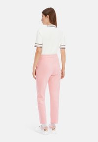 White textured short-sleeve top with brown stripes, paired with light pink corduroy pants, and white sneakers with pink accents.