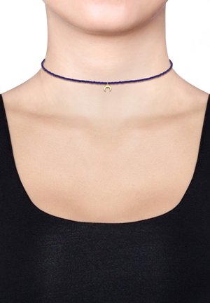 Blå flettet choker-nedhalskæde med en lille guld halvmånecharme i midten. Glat tekstur, enkelt design.