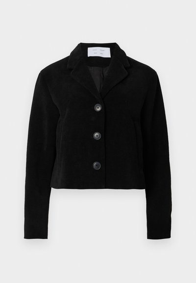 Fekete kordbársony rövidített kabát, kerekített gallérral, négy gombos záródással és két oldalzsebbel. Texturált szövet, sima béléssel.