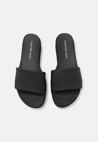 Sandales à glissière noires avec une sangle en textile lisse et un coussin de pied rembourré. Présente un texte logo sur la semelle intérieure. Design minimaliste et semelle plate.