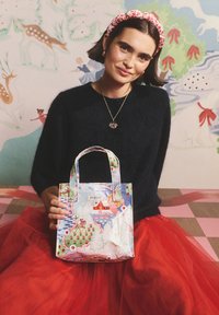 Majhna, barvita torba za prenašanje z ulično zasnovo pokrajine, ki vključuje drevesa, živali in srca. Izdelana iz sijočega materiala z dvojnimi ročaji.