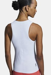 Witte sportieve tanktop met hoge hals, racerback ontwerp, een gladde textuur en minimale branding in het zwart aan de onderlinkerzijde.