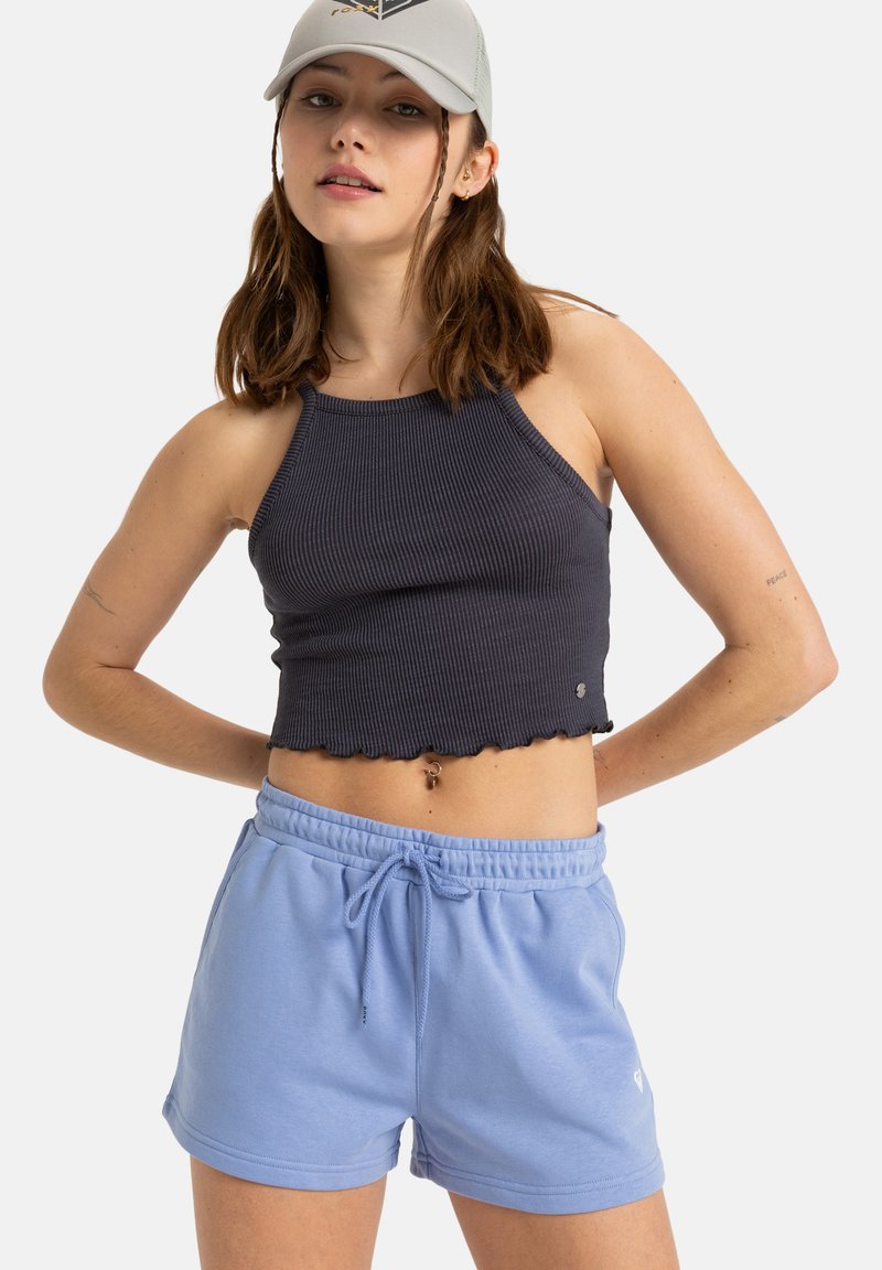 Czarny prążkowany top crop z falbanką, zestawiony z jasnoniebieskimi szortami na sznurki, wykonanymi z miękkiego materiału. Swobodny strój sportowy.