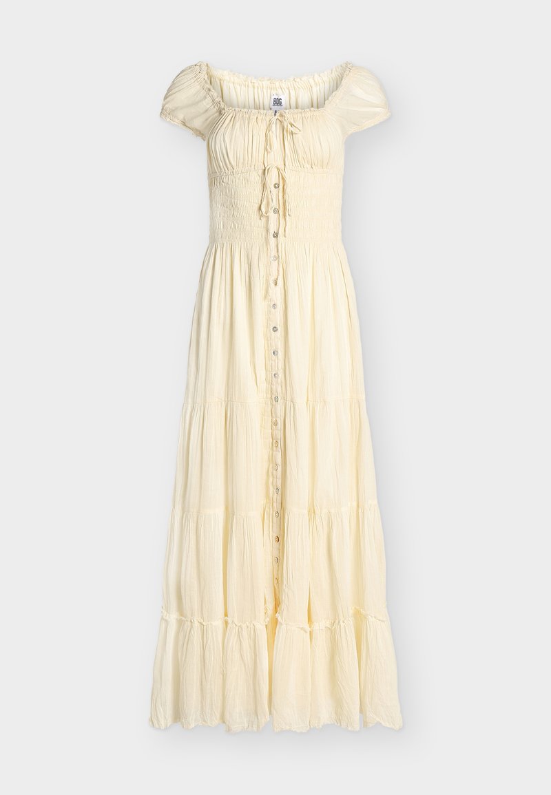 Φόρεμα μήκους μέχρι τον αστράγαλο σε εκρού χρώμα, με στρώσεις, κοντά φουσκωτά μανίκια, σφηκοφωλιά στο στήθος, κουμπιά μπροστά και έναν μικρό κόμπο στο λαιμό.