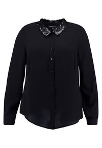 Zwarte blouse van gladde stof, met een collier van pailletten, knopen aan de voorkant en lange mouwen. Zachte textuur en licht afgeronde zoom.