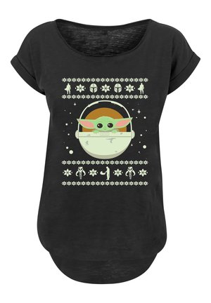 Schwarzes T-Shirt mit kurzen Ärmeln, das ein hellgrünes Grafikdesign eines Wesens in einer Kapsel zeigt, umgeben von dekorativen Mustern und Symbolen.
