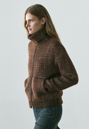 Brązowy sweter na zamek w kratę z wysokim kołnierzem, wykonany z teksturowanej mieszanki wełny. Posiada dopasowany krój i dwie boczne kieszenie.