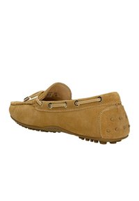 Beige Wildleder-Mokassinschuh mit einer abgerundeten Zehenpartie, kontrastierenden Nähten und einer Gummisohle, die erhabene Punkte für besseren Halt aufweist. Schnürsenkel und Ösen sind akzentuiert.