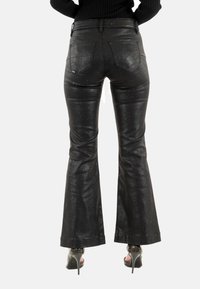 Pantaloni neri a zampa d'elefante con una texture lucida e un delicato luccichio. Presentano una vita media, un design a cinque tasche e una silhouette aderente.