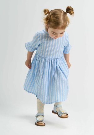 Sinine triibuline kleit lühikeste puffvarrukatega, kokku gatherdatud talje ja lahtine seelik. Laste jalatsiteks on sinised sandaalid lilleliste kaunistustega.