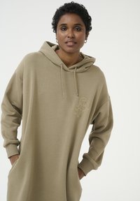 Khaki hoodie jurk van zachte stof, met een voork pocket en geborduurd logo in een tonale tint. Capuchon met kreegaccenten.