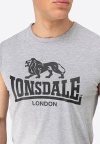 Gray sleeveless t-shirt featuring a large black lion graphic with the text "LONSDALE LONDON" in bold lettering underneath.