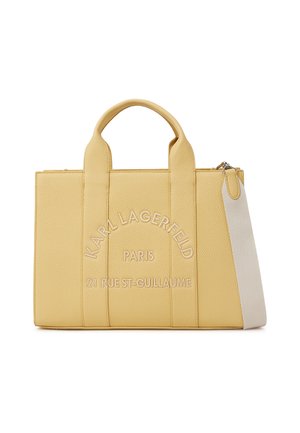 Prostokątna żółta torba typu tote z krótkimi uchwytami, białym paskiem na ramię, tłoczonym napisem "Karl Lagerfeld Paris 21 Rue St-Guillaume" na przedzie.