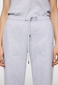 Lichtgrijze sweatpants van zachte stof met een elastische tailleband, verstelbaar trekkoord en klein logo aan de linkerkant.