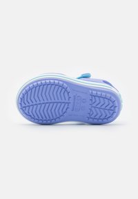 Purple rubber shoe with a textured outsole featuring a wave pattern. Lightweight design with an adjustable strap and contrasting white accents.
