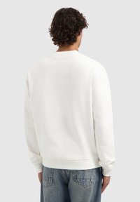 Witte katoenen sweatshirt met ribgebreide manchetten en zoom, ontwerp met ronde hals en een gladde textuur, gedragen met lichtblauwe denim jeans.