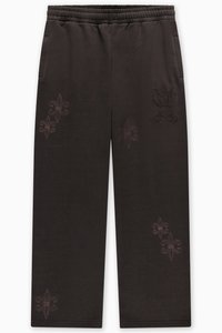 Fekete melegítőnadrág elasztikus derékpánttal, oldalzsebekkel és világos szálból hímzett virágmintákkal a lábakon. Simább tapintású anyag.