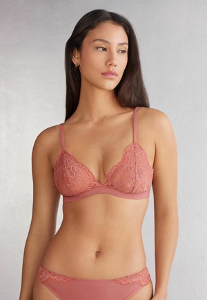Roze kant bralette met een driehoekige vorm, zachte stof, verstelbare bandjes en een gladde band. Gecombineerd met bijpassende slipjes met kantafwerking.