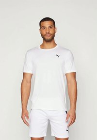 Camiseta atlética blanca hecha de tejido ligero, con cuello redondo y mangas cortas. Logo negro de Puma en el lado izquierdo del pecho.